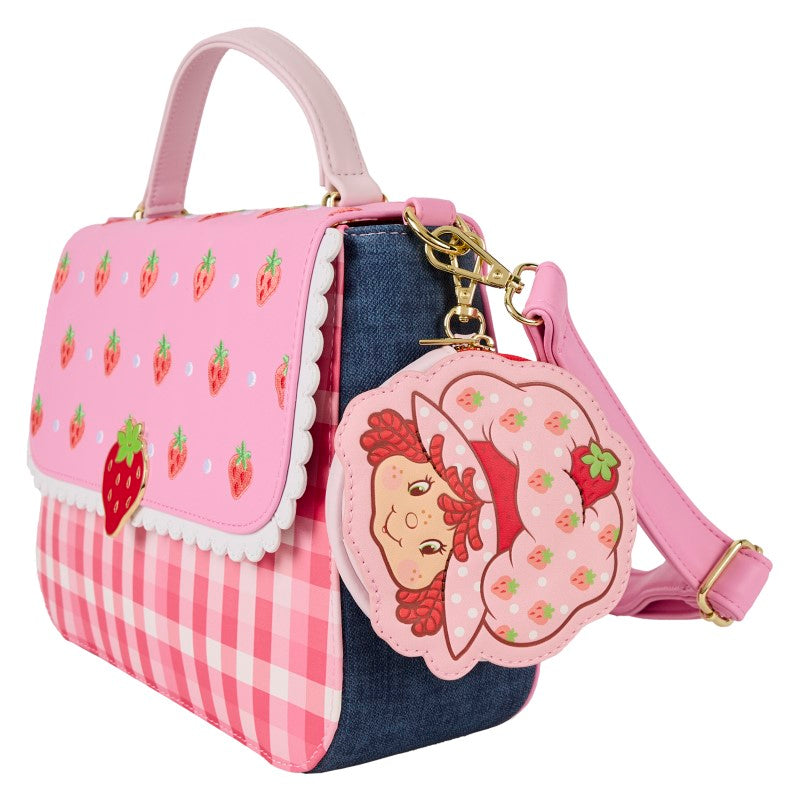 Sac à main Loungefly Charlotte aux Fraises rose vichy et denim, accompagné d'un porte-monnaie accroché au sac avec la tête de Charlotte, vue sur le côté